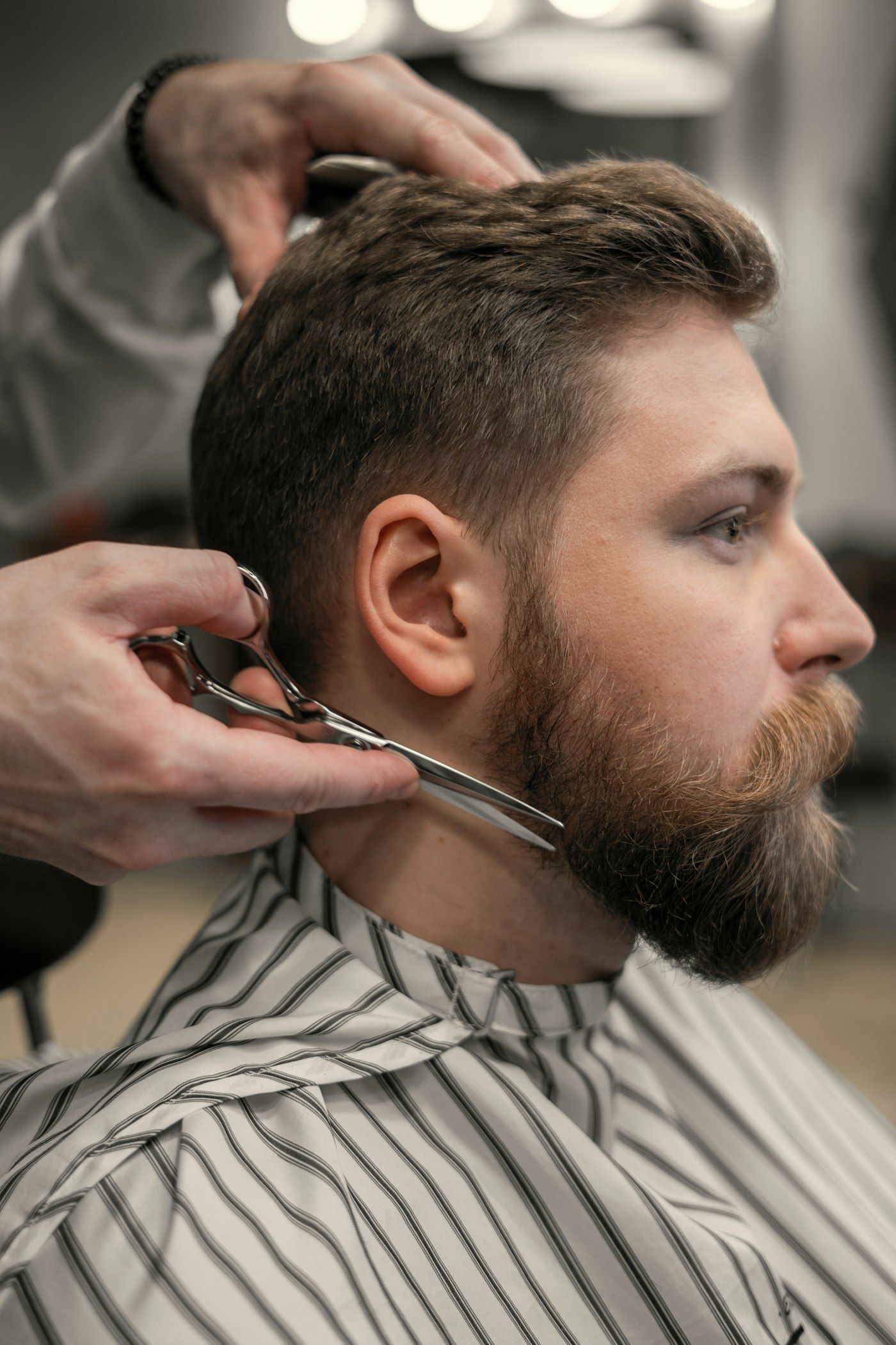 Stand-in Unsplash photo of a barber shaping a full beard with scissors