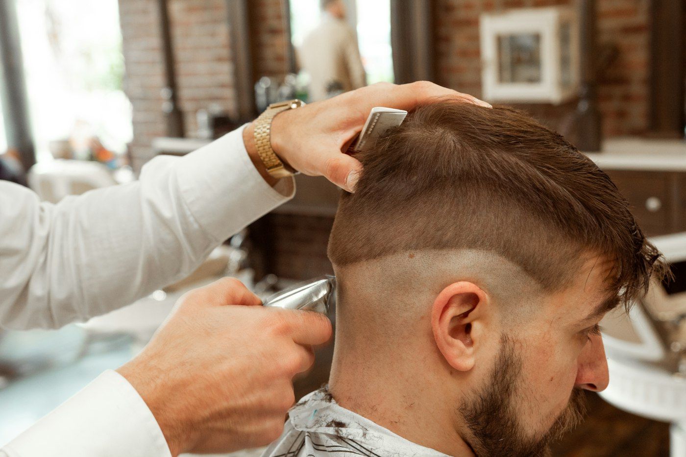 Stand-in Unsplash photo of a barber fading the back of a client's head with clippers and a comb